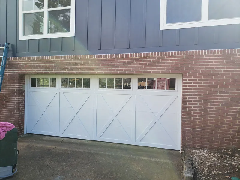 A new white carriage-style door with X bracing and windows