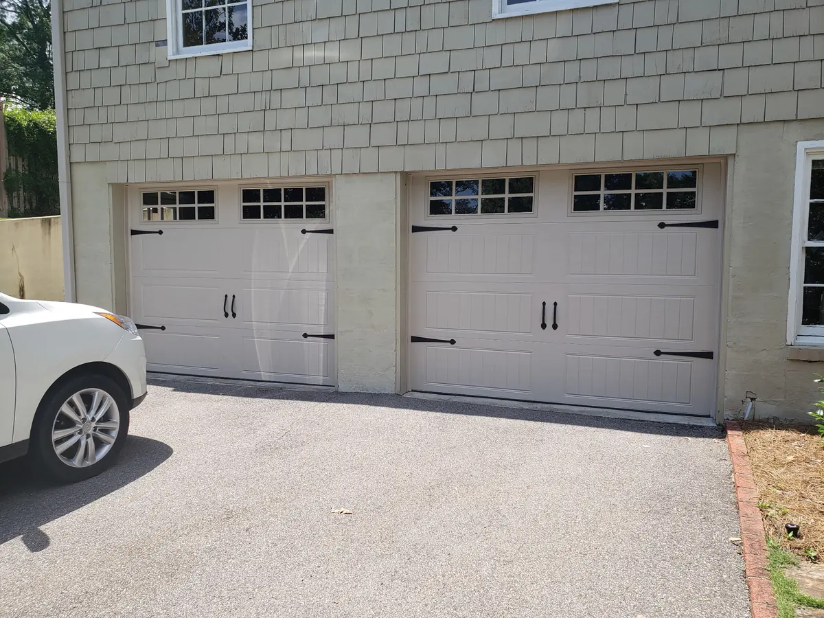Two carriage-style garage doors with black hardware on a shingle-sided house