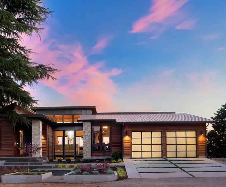 A modern house at dusk with its garage doors lit