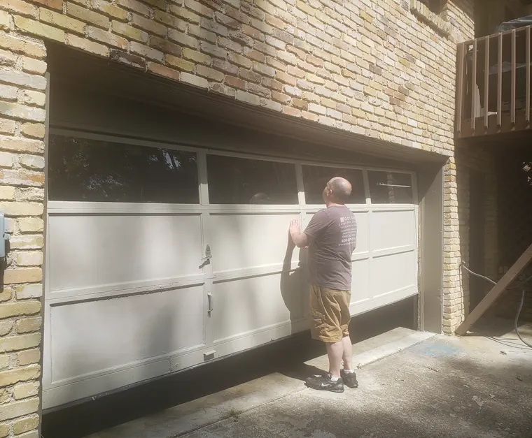A garage door being worked on at a brick house