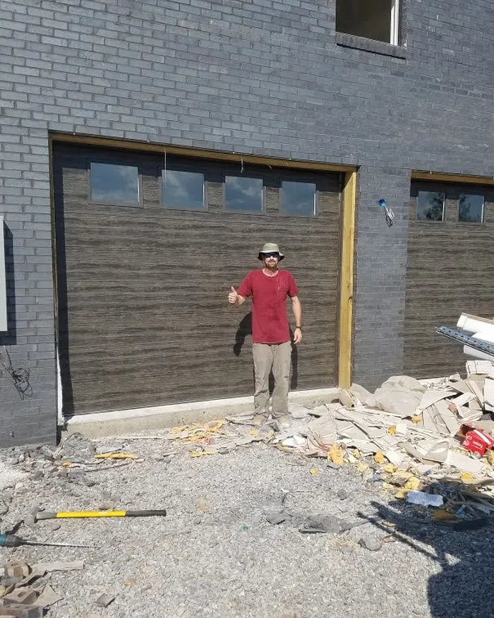 A newly installed dark wood-look garage door at a job site