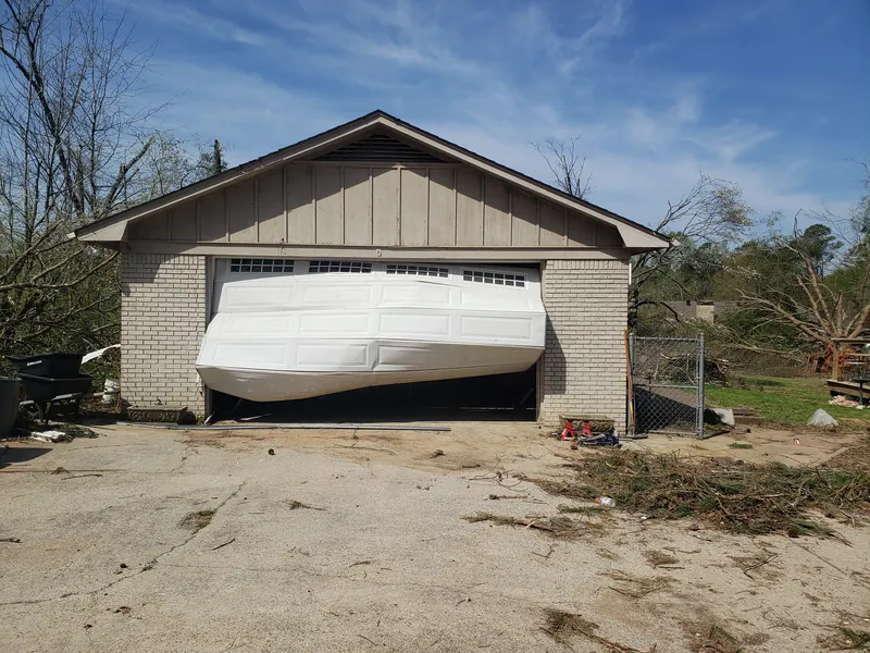 A garage door crushed and bent out of its opening